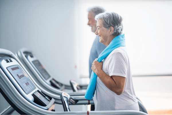 Treadmill-Benefits-and-Disadvantages-smiling-couple-each-using-a-treadmill